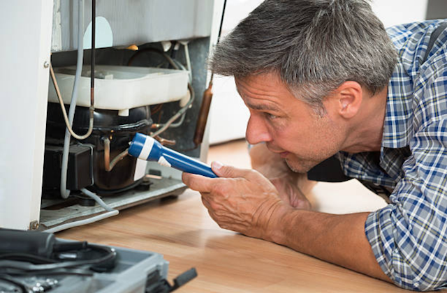 repairman under refrigerator